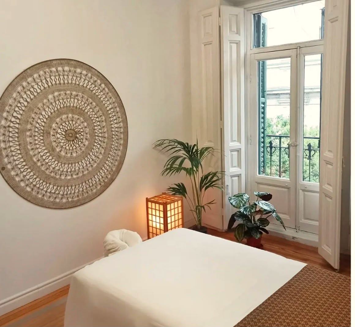 Sala de tratamiento de Espacio Enlaza: camilla, lámpara de papel, plantas y balcón con luz natural